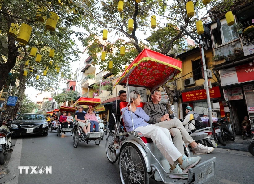 Du khách nước ngoài sử dụng xích lô thưởng ngoạn nét đẹp cổ kính của Phố cổ Hà Nội. Ảnh: TTXVN