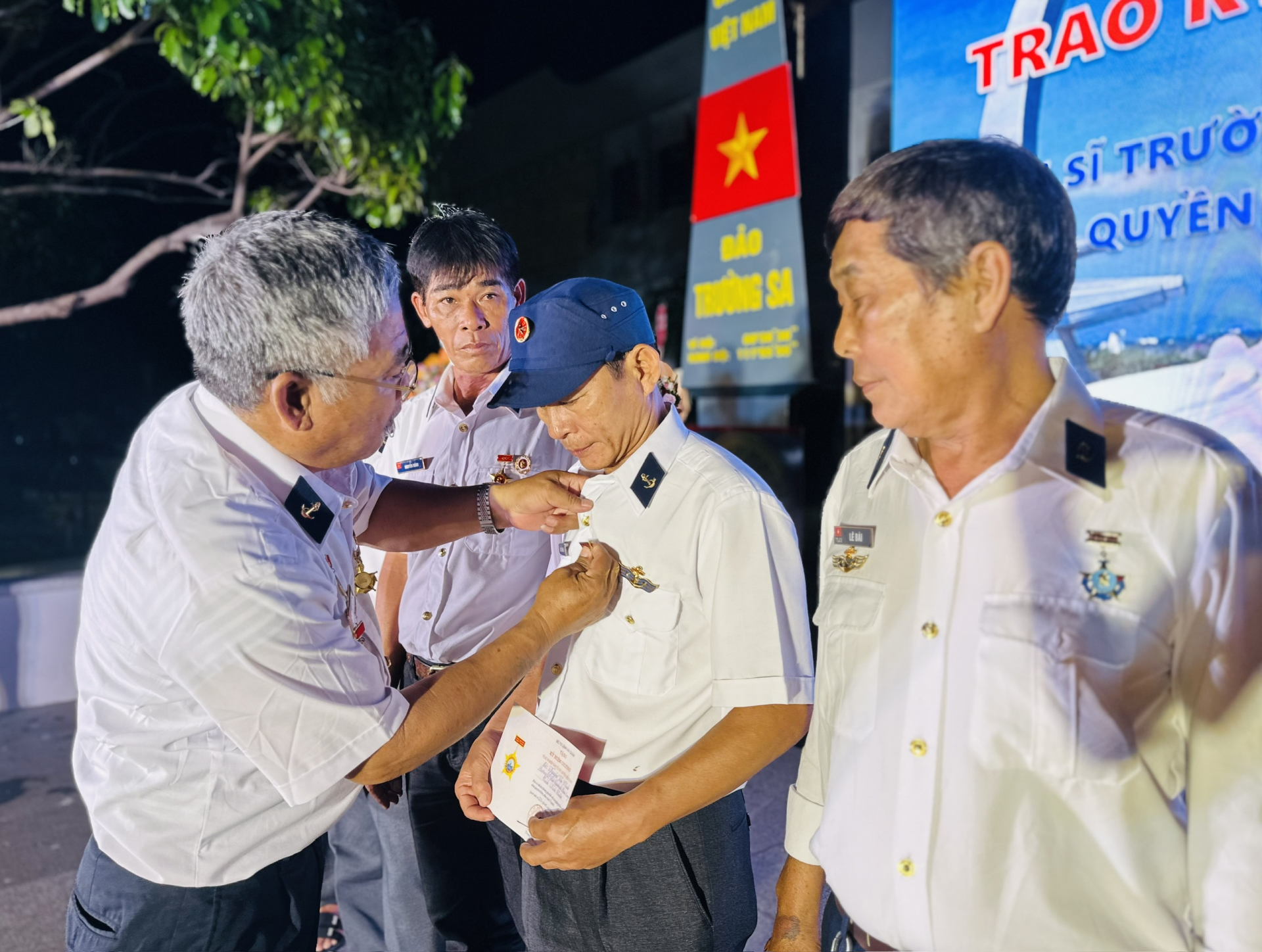 Thừa ủy quyền, cựu chiến binh Trần Văn Xuất, Trưởng ban Liên lạc cựu chiến binh đảo Trường Sa Đông, trao kỷ niệm chương “Vì sự nghiệp bảo vệ chủ quyền biển đảo” cho các cựu chiến binh Trường Sa. Ảnh: YÊN LAN