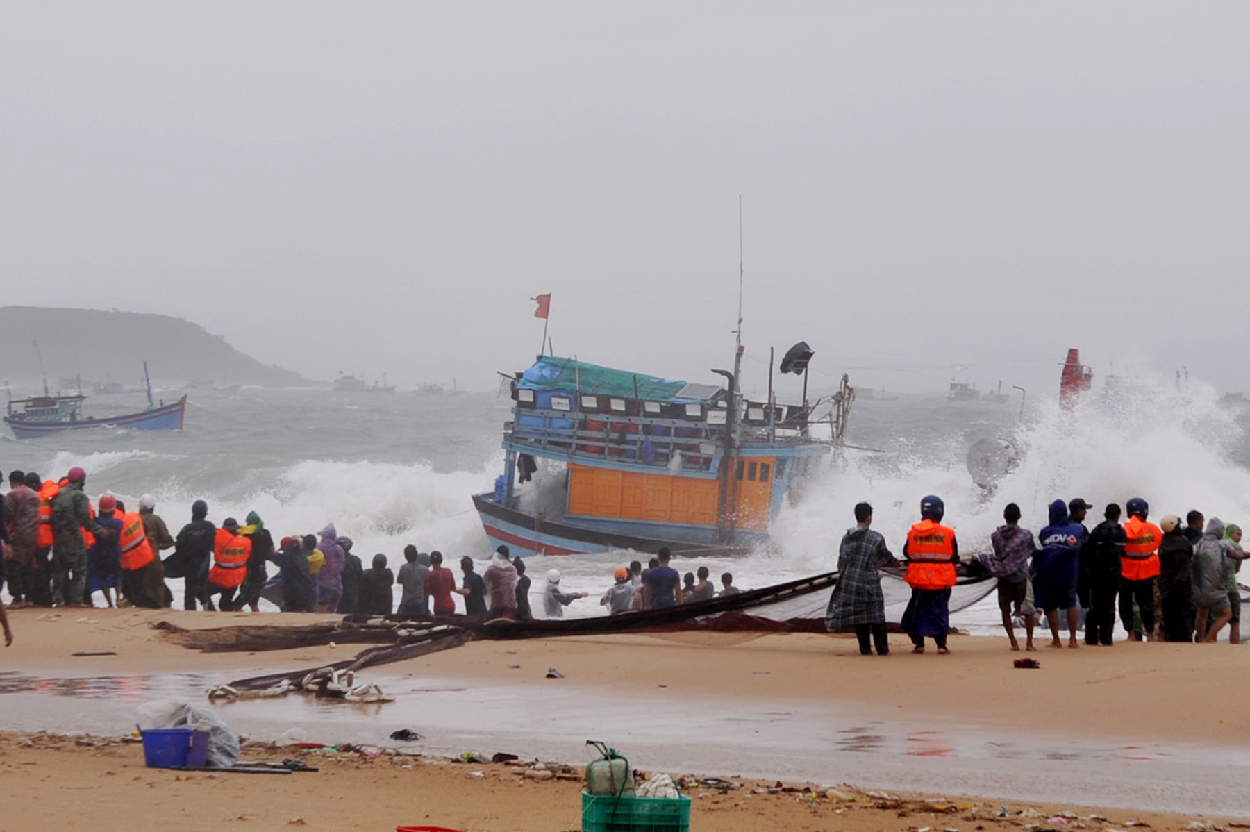 The military forces, police, and local residents rescuing a fishing vessel in Tuy An District that was sunk by sea waves