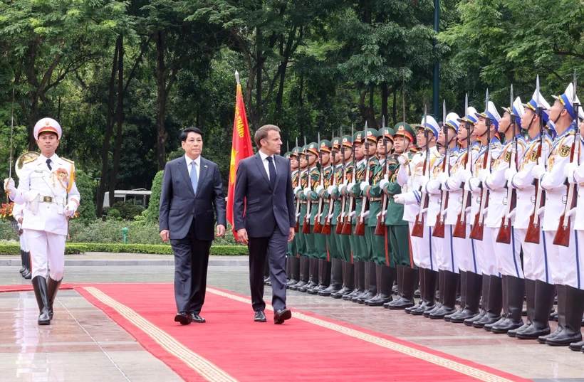 State President Luong Cuong (left) and French President Emmanuel Macron review the Guard of Honour of the Vietnam People’s Army. Photo: VNA