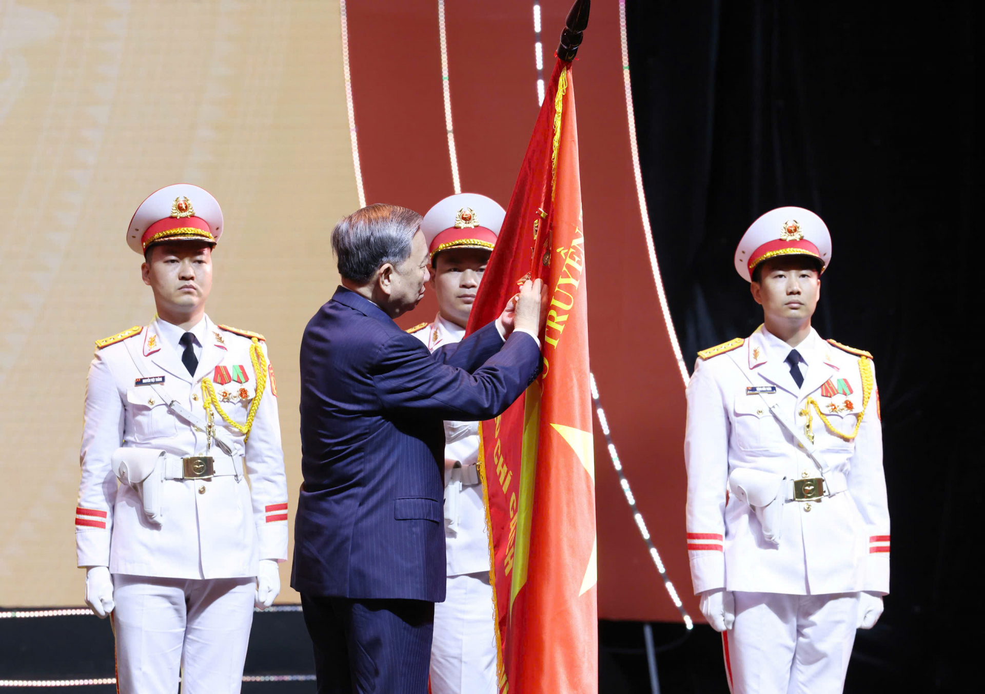Tổng Bí thư Tô Lâm trao tặng Huân chương Hồ Chí Minh thực hiện nghi thức gắn Huân chương Hồ Chí Minh lên cờ truyền thống. Ảnh: HÀ MY