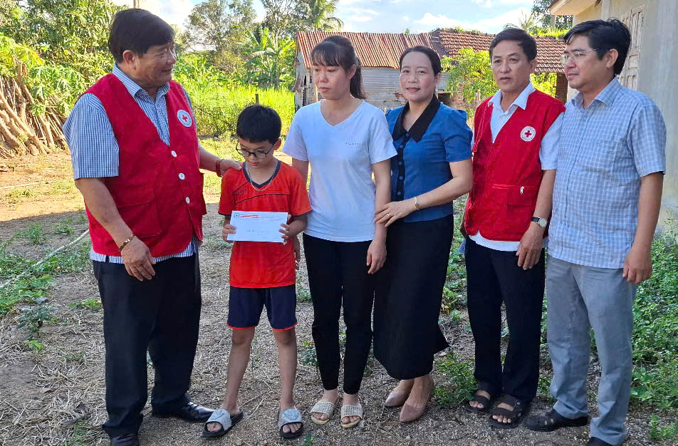 Lãnh đạo Hội Chữ thập đỏ tỉnh và đại điện địa phương trao tặng tiền cho cháu Bạch Thái Phong, ở xã Xuân Quang 3 (huyện Đồng Xuân). Ảnh: MẠNH LÊ TRÂM